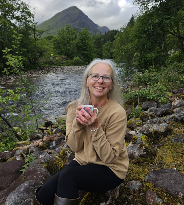 Portrait of Wendy Jennings sitting by a river with a mountion in the background